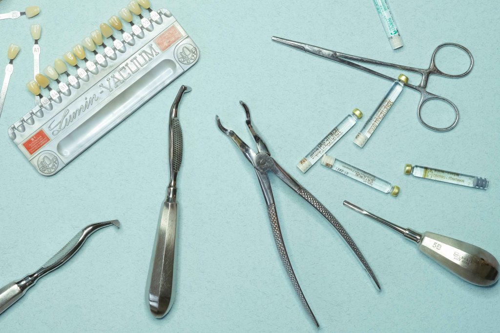 Dental instruments, tooth shade guide, and anaesthetic ampoules arranged on a blue surface