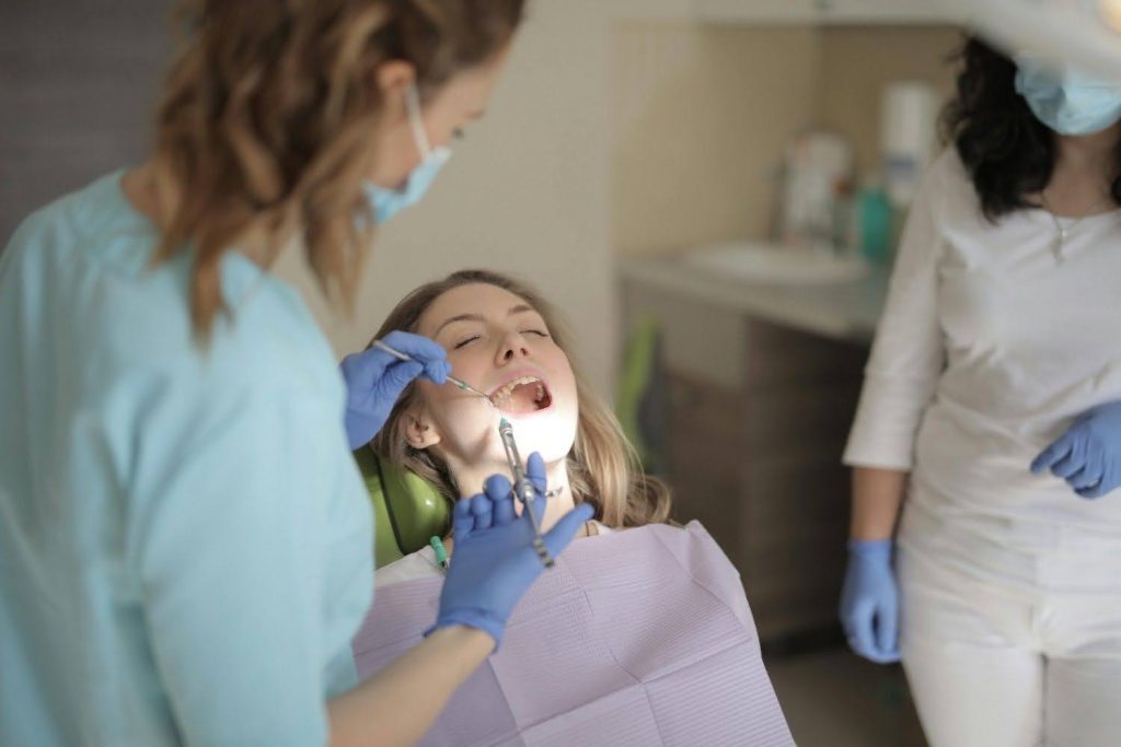 Dentist examining patient’s teeth with dental instruments in a modern clinic