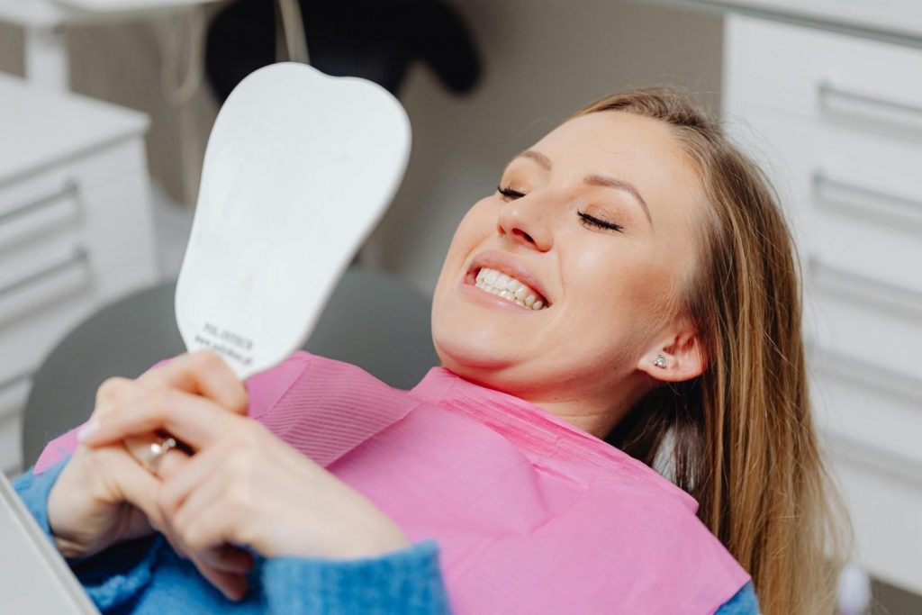 A smiling patient in a dentist chair looking in a mirror