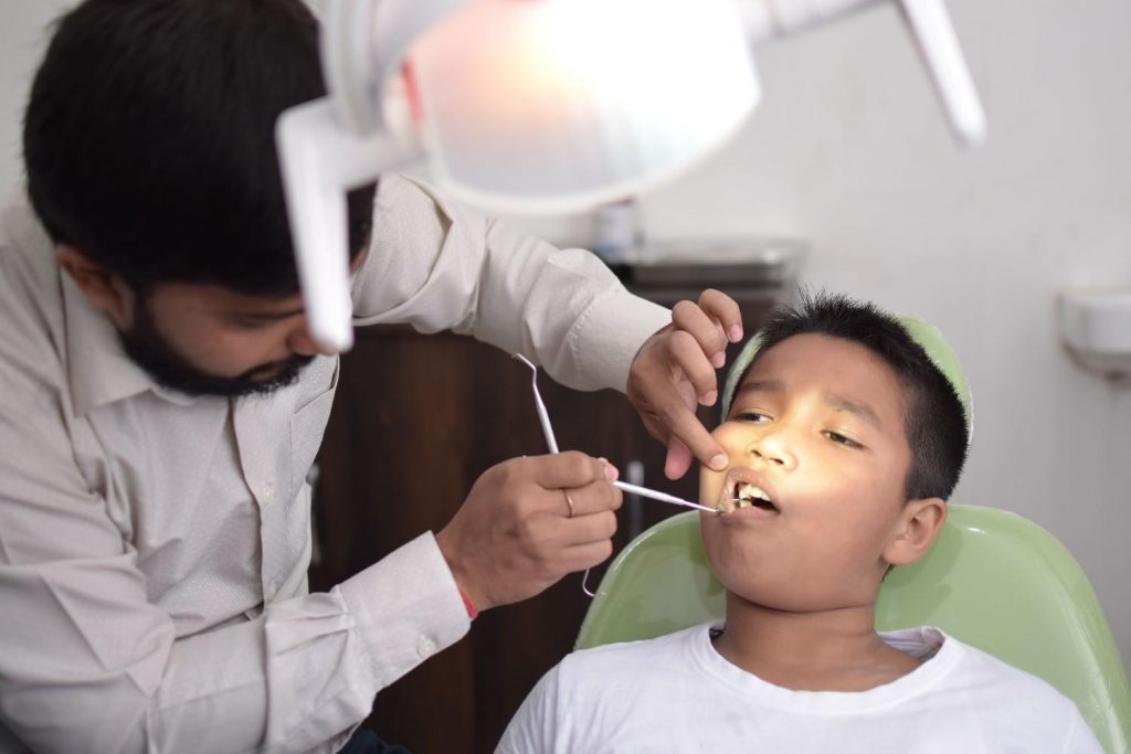 A dentist checks a child's teeth in a well-lit dental clinic