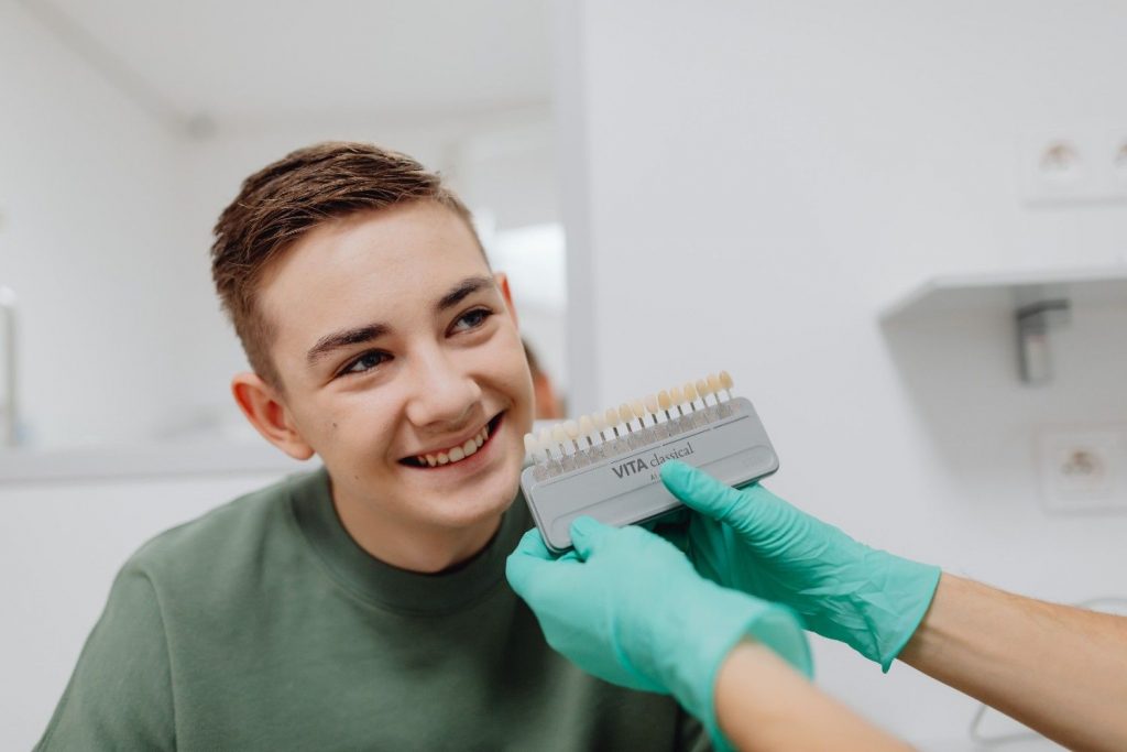 A teenager smiling during a dental shade matching procedure