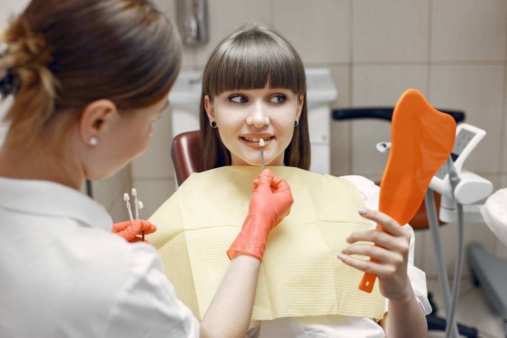 Dentist consults a young woman on veneers using dental tools