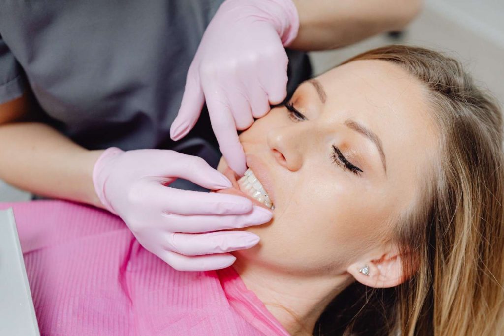 A dentist wearing gloves examines a patient's teeth