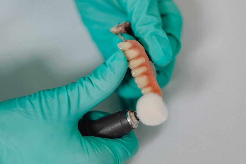 Close-up of a dental professional wearing gloves polishing dentures with care