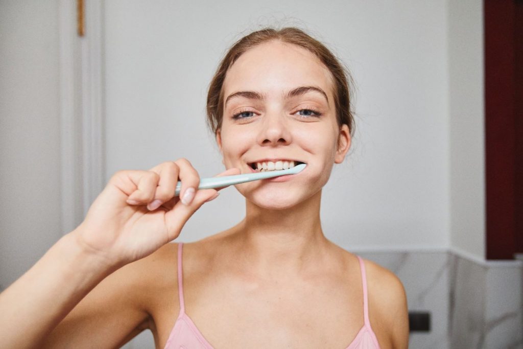 Close-up of a woman smiling while brushing teeth in a modern bathroom