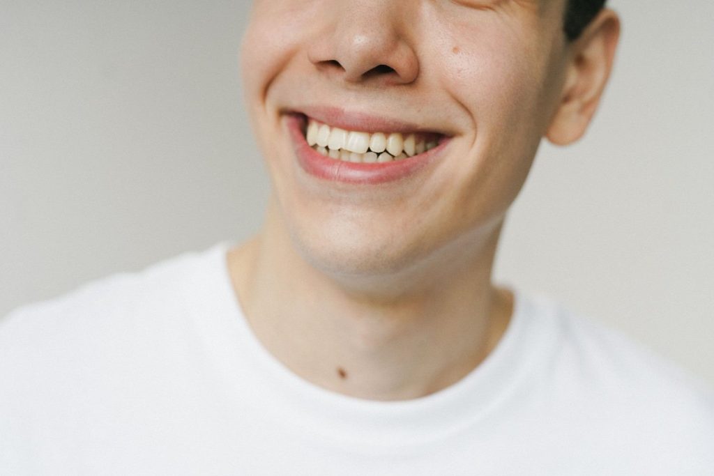 A close-up shot of a young man smiling, highlighting his teeth and expression